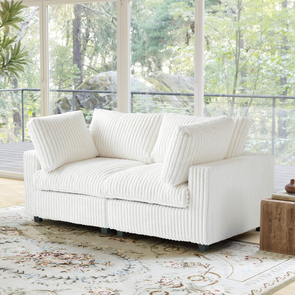 White faux rabbit fur sofa in a room with large windows and a decorative rug.