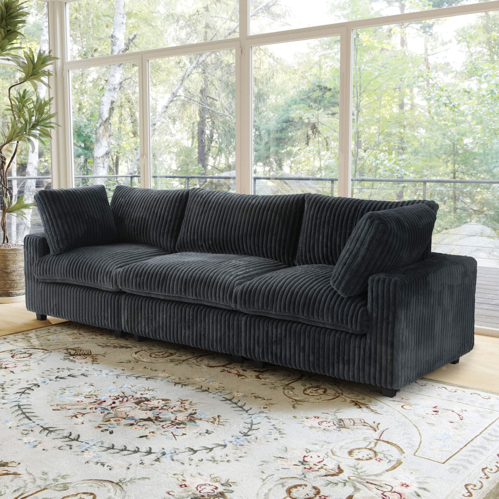 Black faux rabbit fur 3-seat sofa in a living room with large windows and a decorative rug.