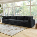 Large black faux rabbit fur 4-seat sofa in a living room with large windows and a rug.
