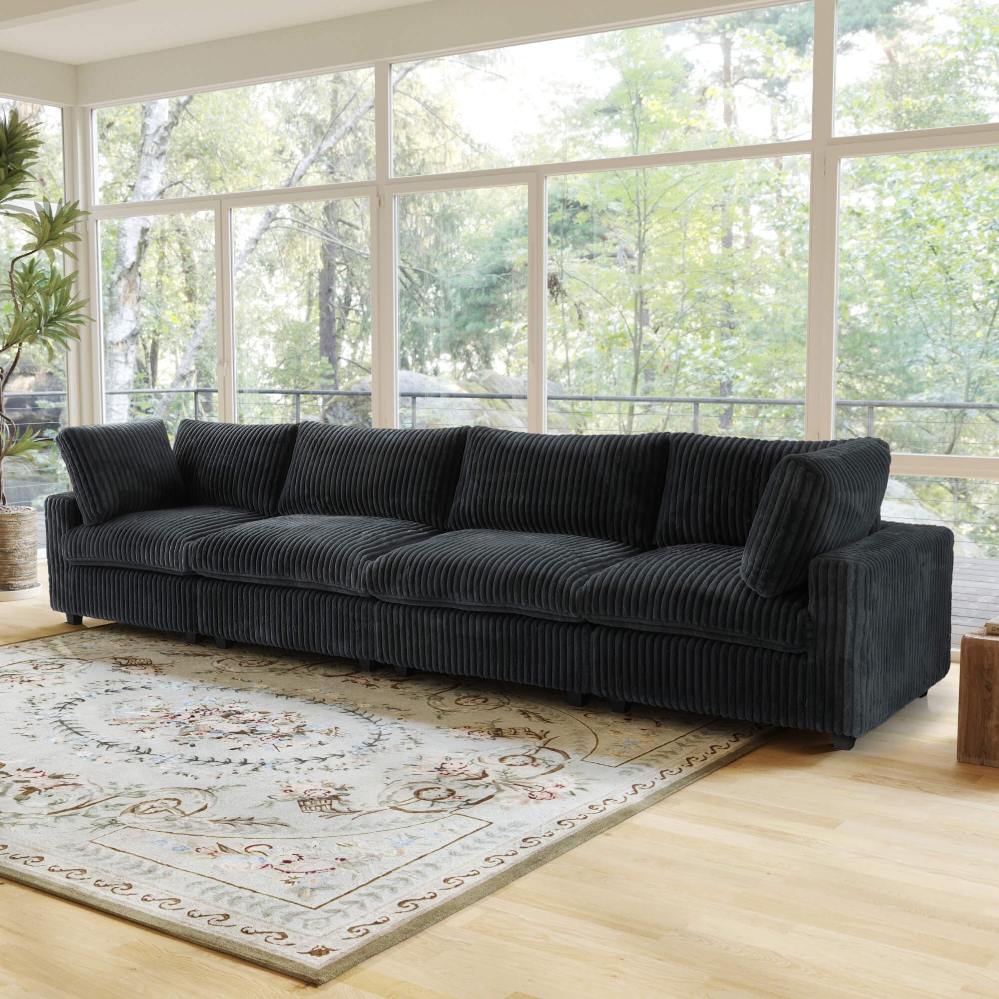 Large black faux rabbit fur 4-seat sofa in a living room with large windows and a rug.
