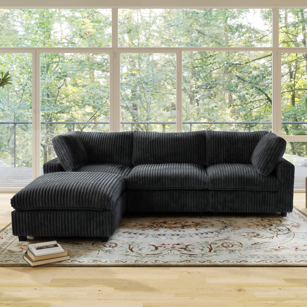 Black L-shaped sectional sofa in a room with large windows and a rug.