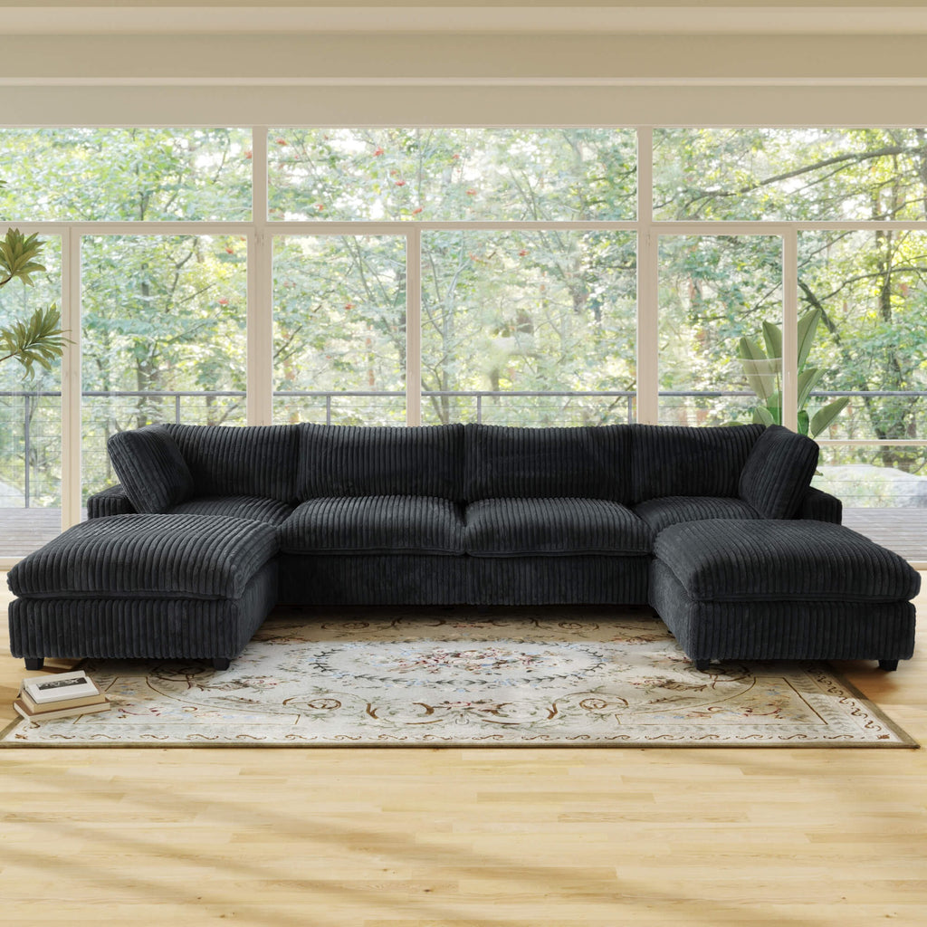 Black U-shaped sectional sofa in a living room with large windows and greenery outside