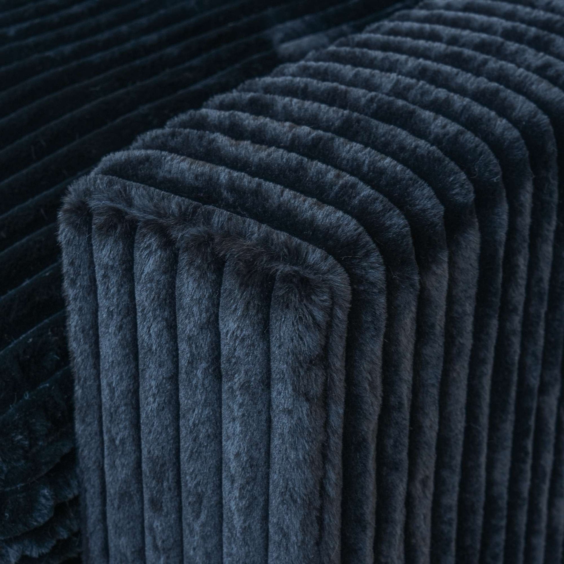 Close-up of a wide armrest of a black faux rabbit fur sofa