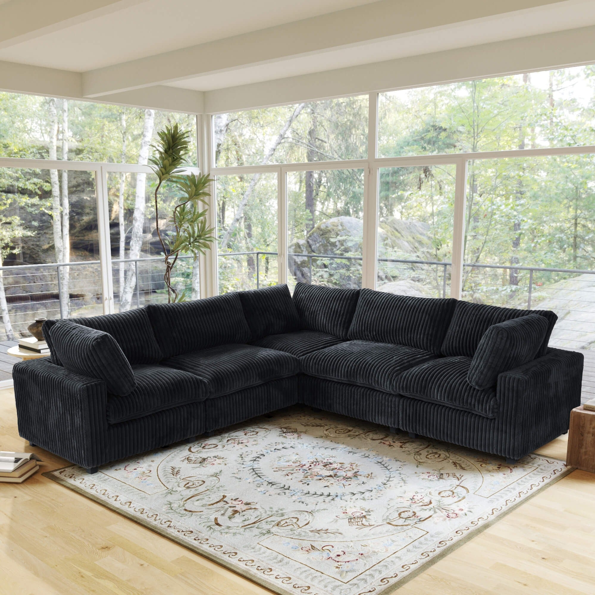 Black corner sectional sofa in a living room with large windows and a decorative rug.