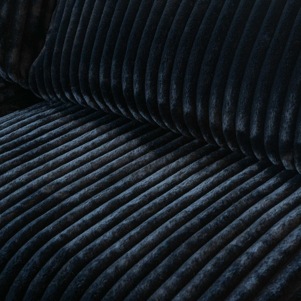 Close-up of a seat of a black faux fur sofa