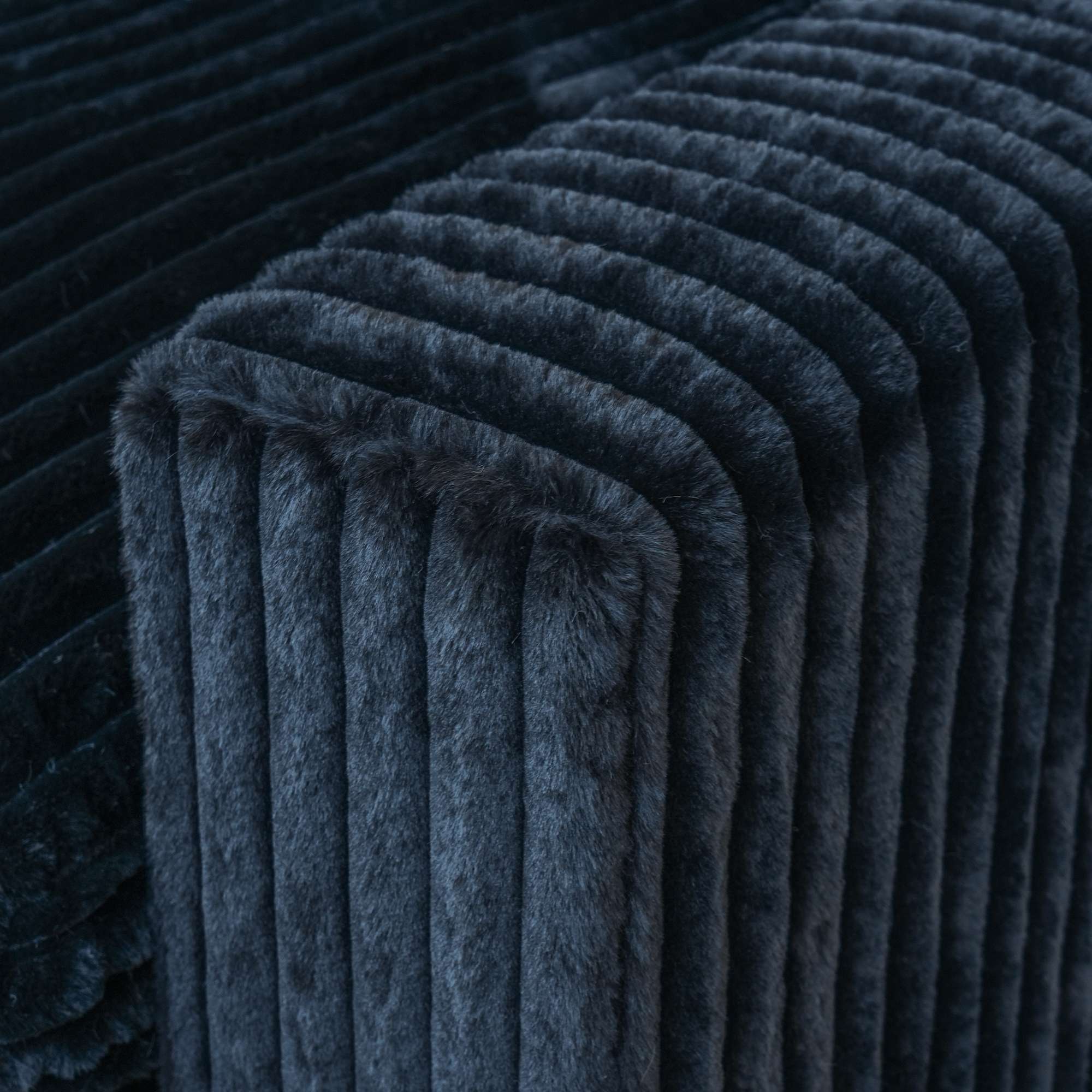 Close-up of a wide armrest of a black faux fur sofa