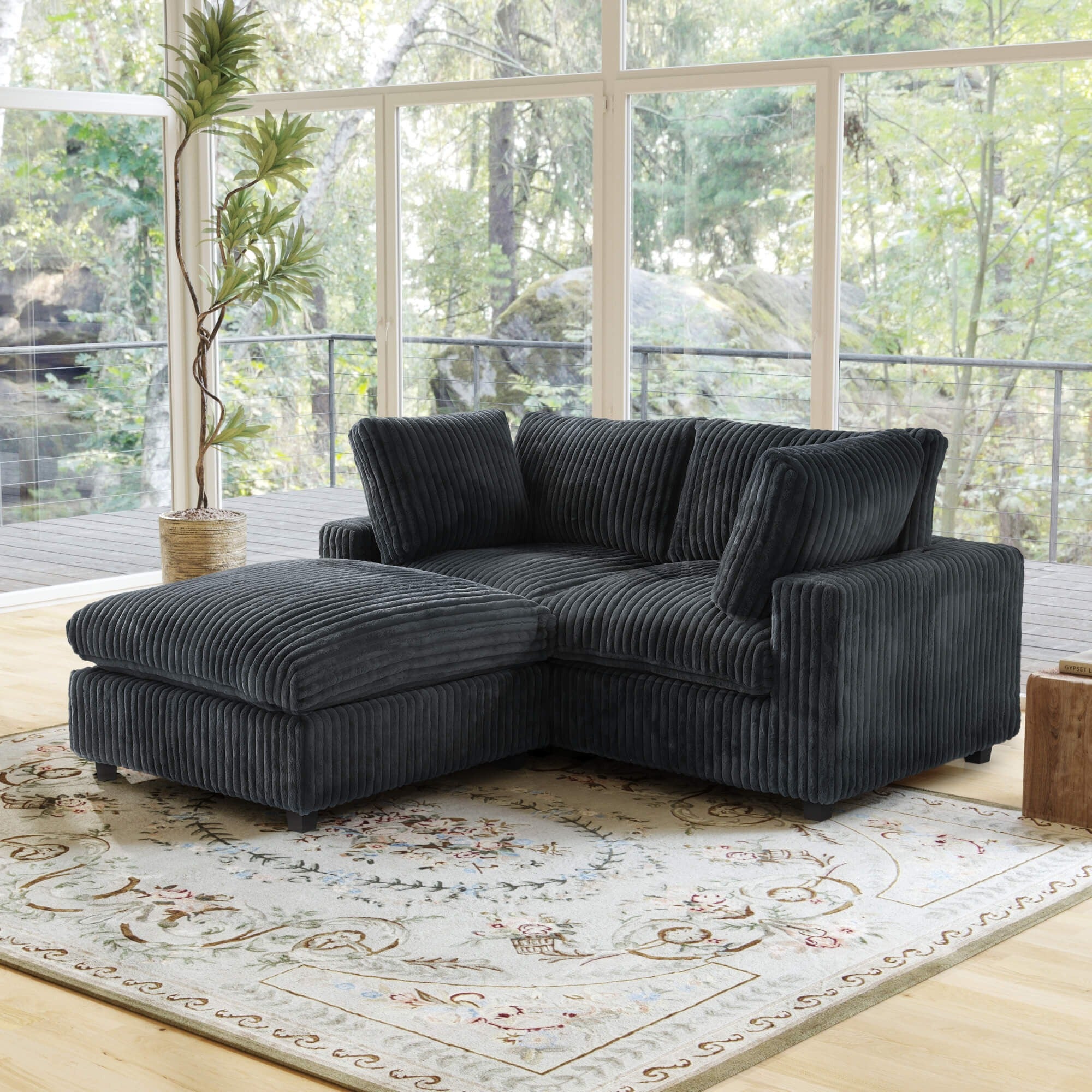 Black faux rabbit fur sectional loveseat sofa with ottoman in a living room with large windows and a decorative rug.
