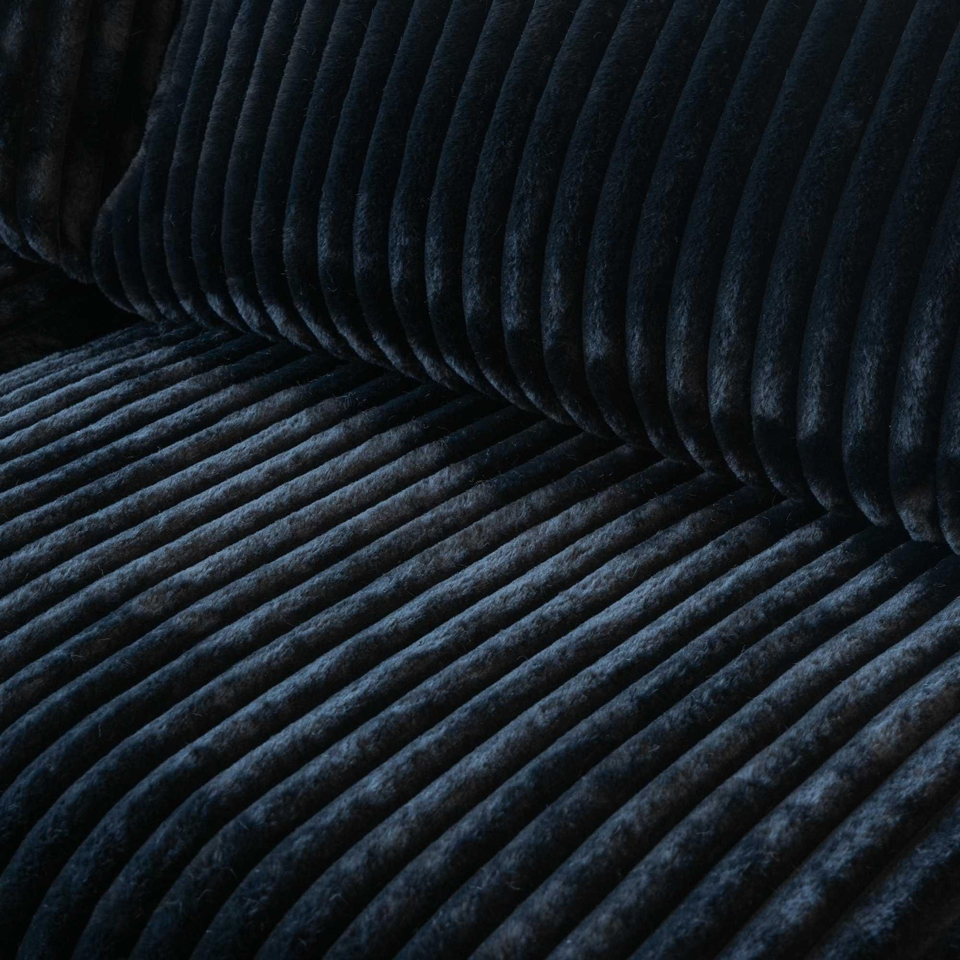 Close-up of a seat of a black faux rabbit fur sofa