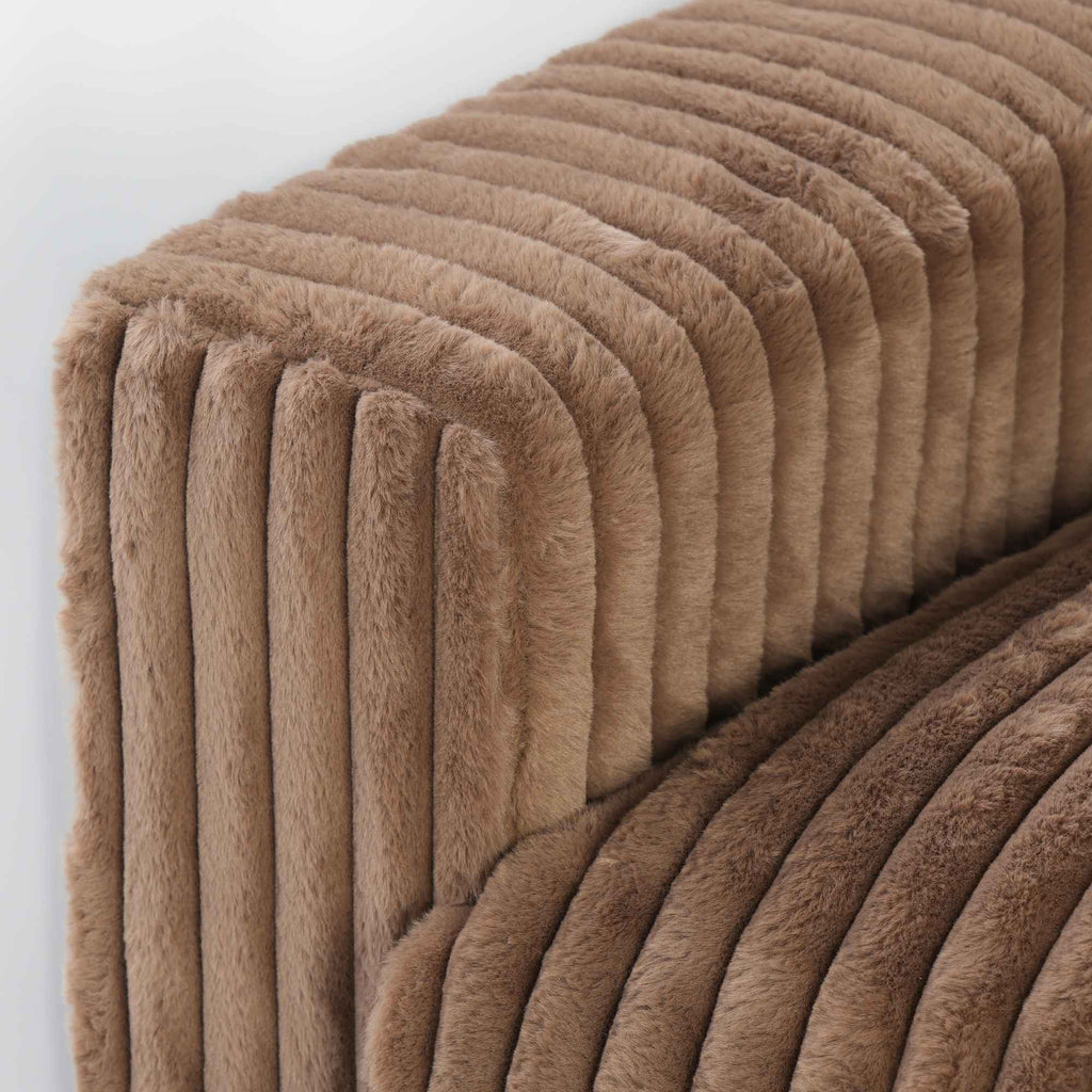 Close-up of a wide armrest of a brown faux rabbit fur sofa