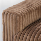 Close-up of a wide armrest of a brown faux rabbit fur sofa