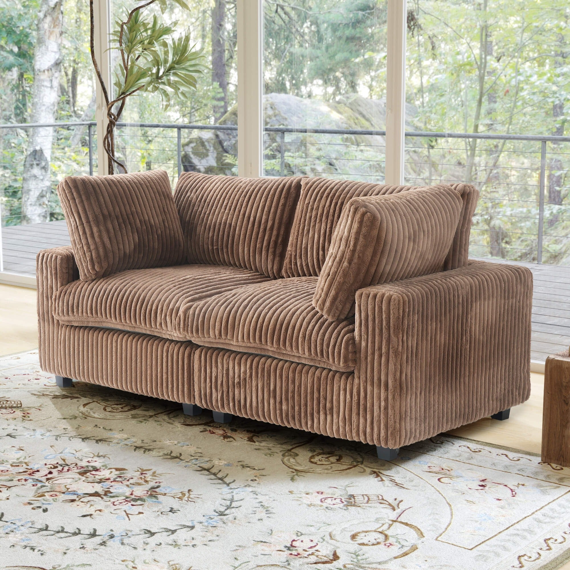 Brown faux rabbit fur sofa in a living room with large windows and greenery outside.