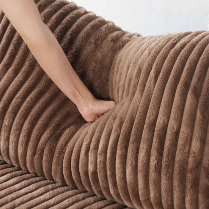 Person pressing on a backrest pillow of a brown faux rabbit fur sofa
