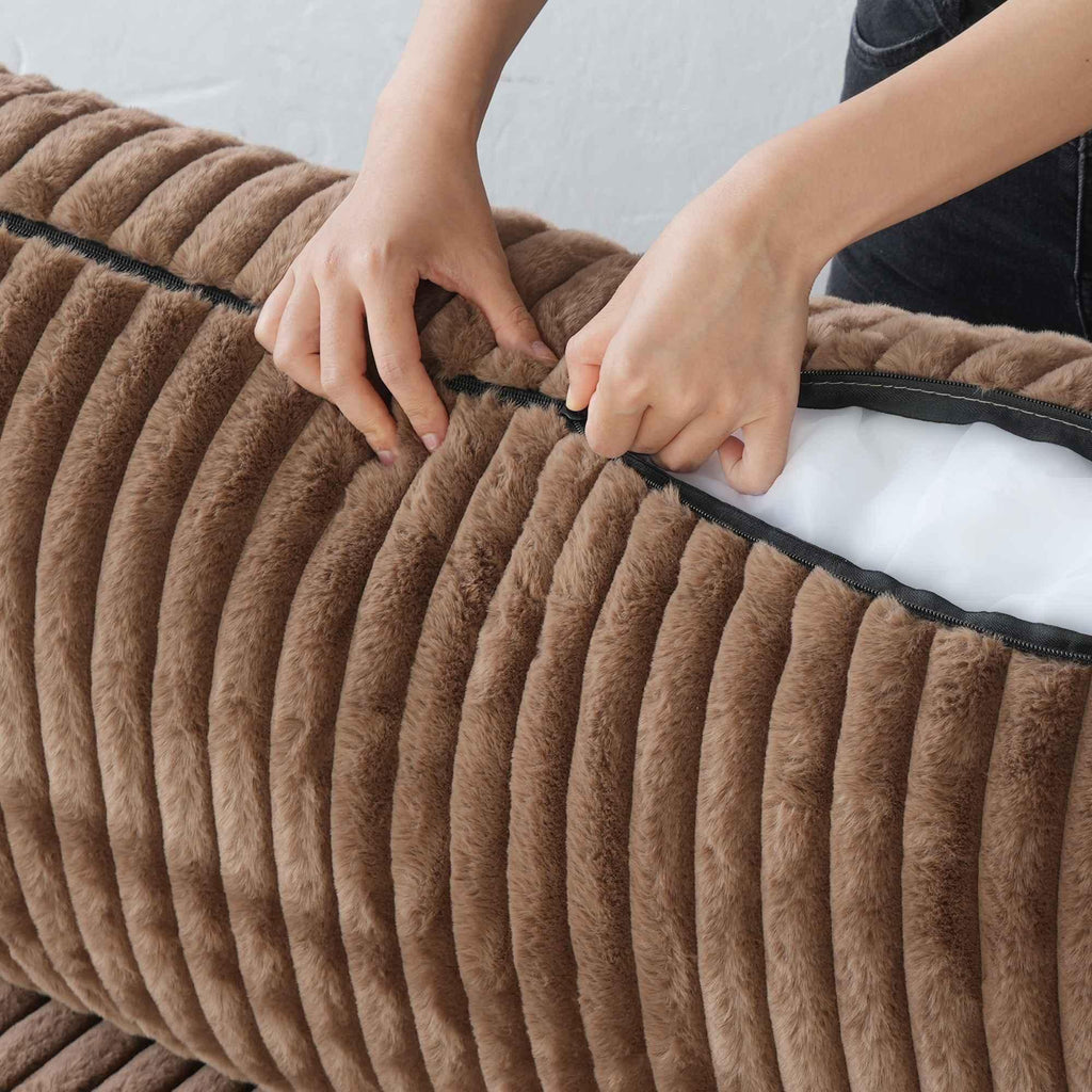 Person unzipping a cushion cover of a brown faux rabbit fur sofa