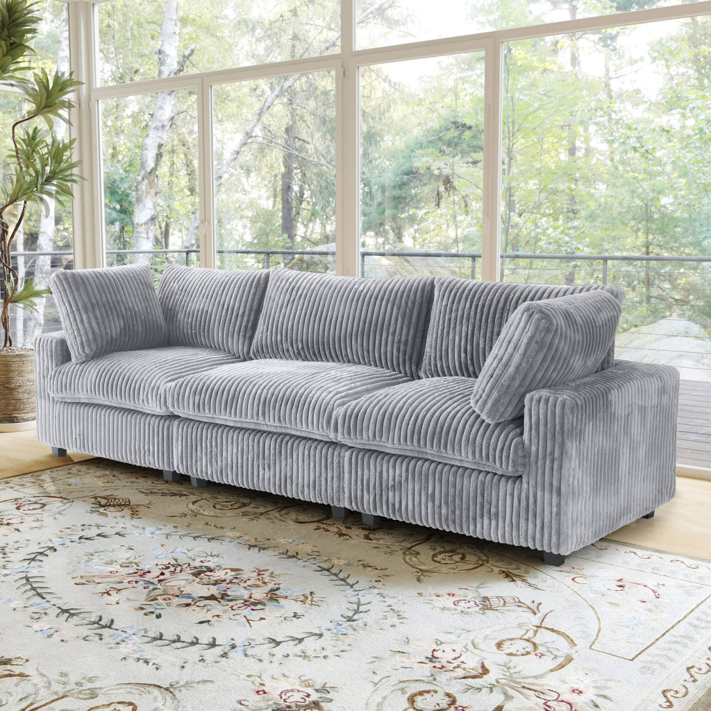 Gray faux rabbit fur 3-seat sofa in a living room with large windows and a decorative rug.