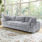 Gray faux rabbit fur 3-seat sofa in a living room with large windows and a decorative rug.