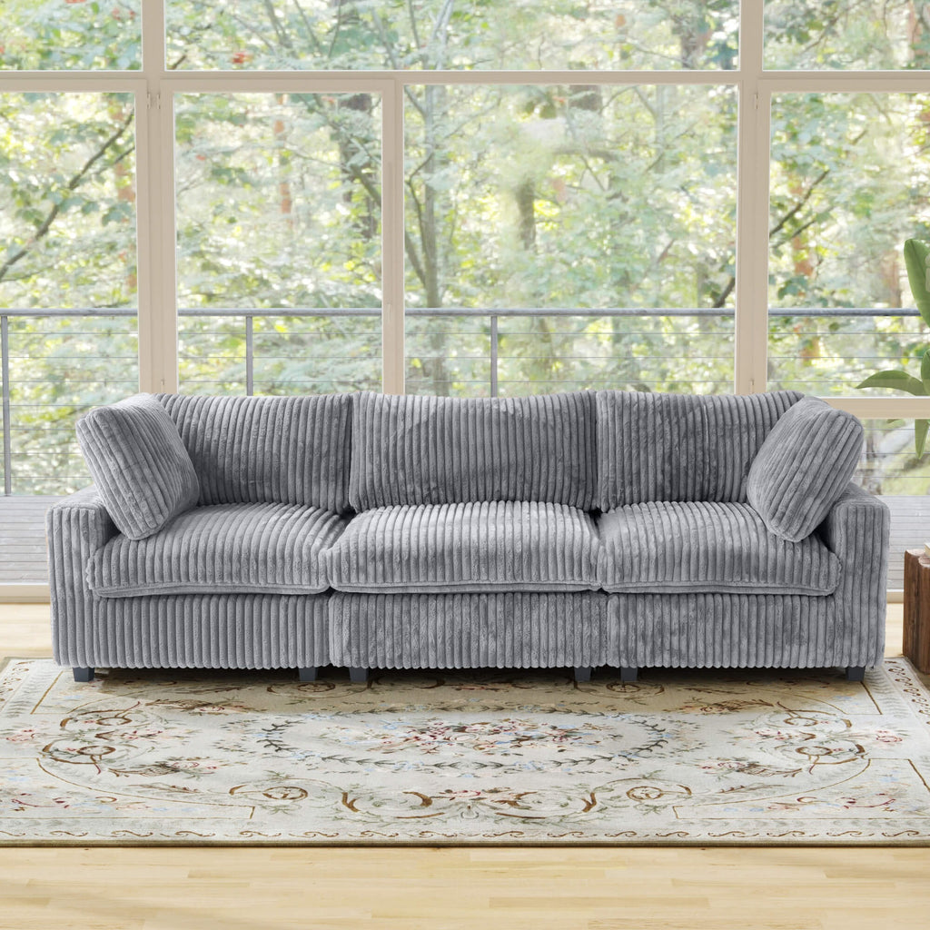 Gray faux rabbit fur 3-seat sofa in a room with large windows and greenery outside