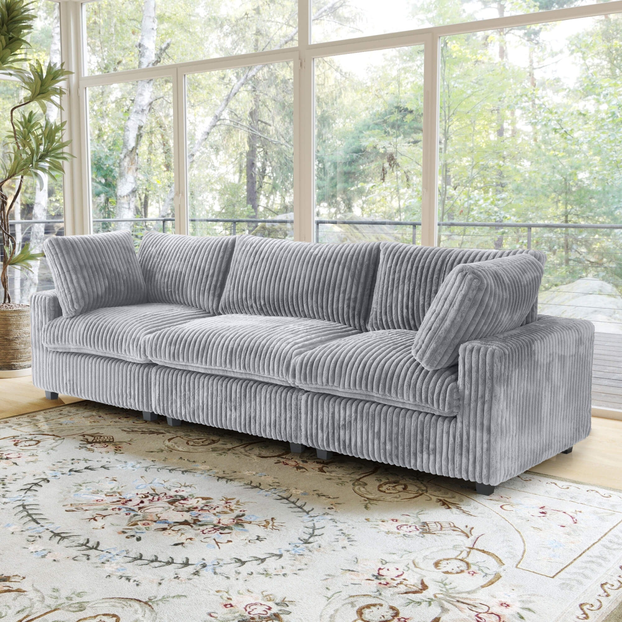 Gray faux rabbit fur 3-seat sofa in a living room with large windows and a decorative rug.