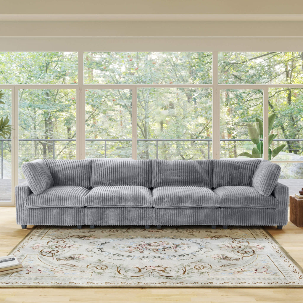 Gray faux rabbit fur 4-seat sectional sofa in a living room with large windows and a decorative rug.