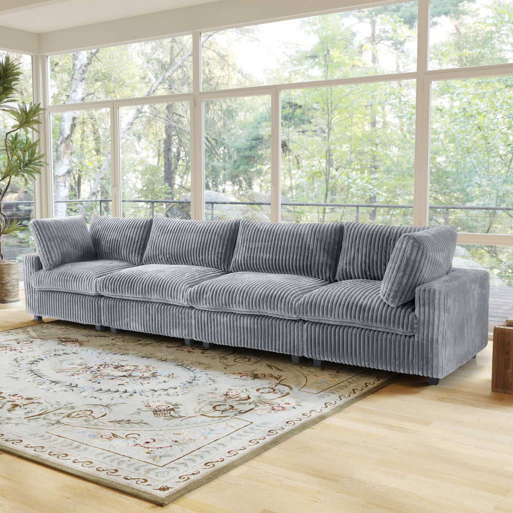 Gray faux rabbit fur 4-seat sofa in a living room with large windows and a rug.