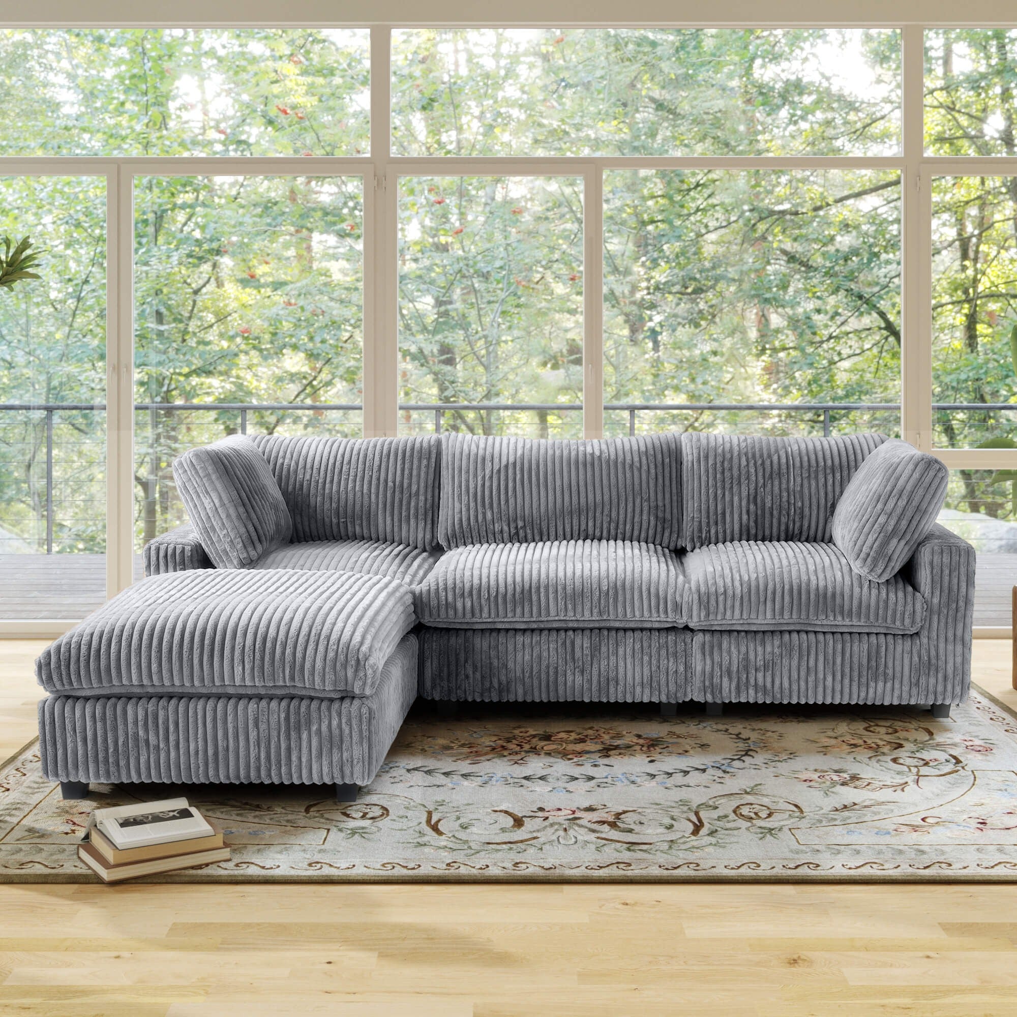 Gray L-shaped sectional sofa in a room with large windows and a rug.