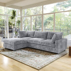 Gray L-shaped sectional sofa in a living room with large windows and a decorative rug.
