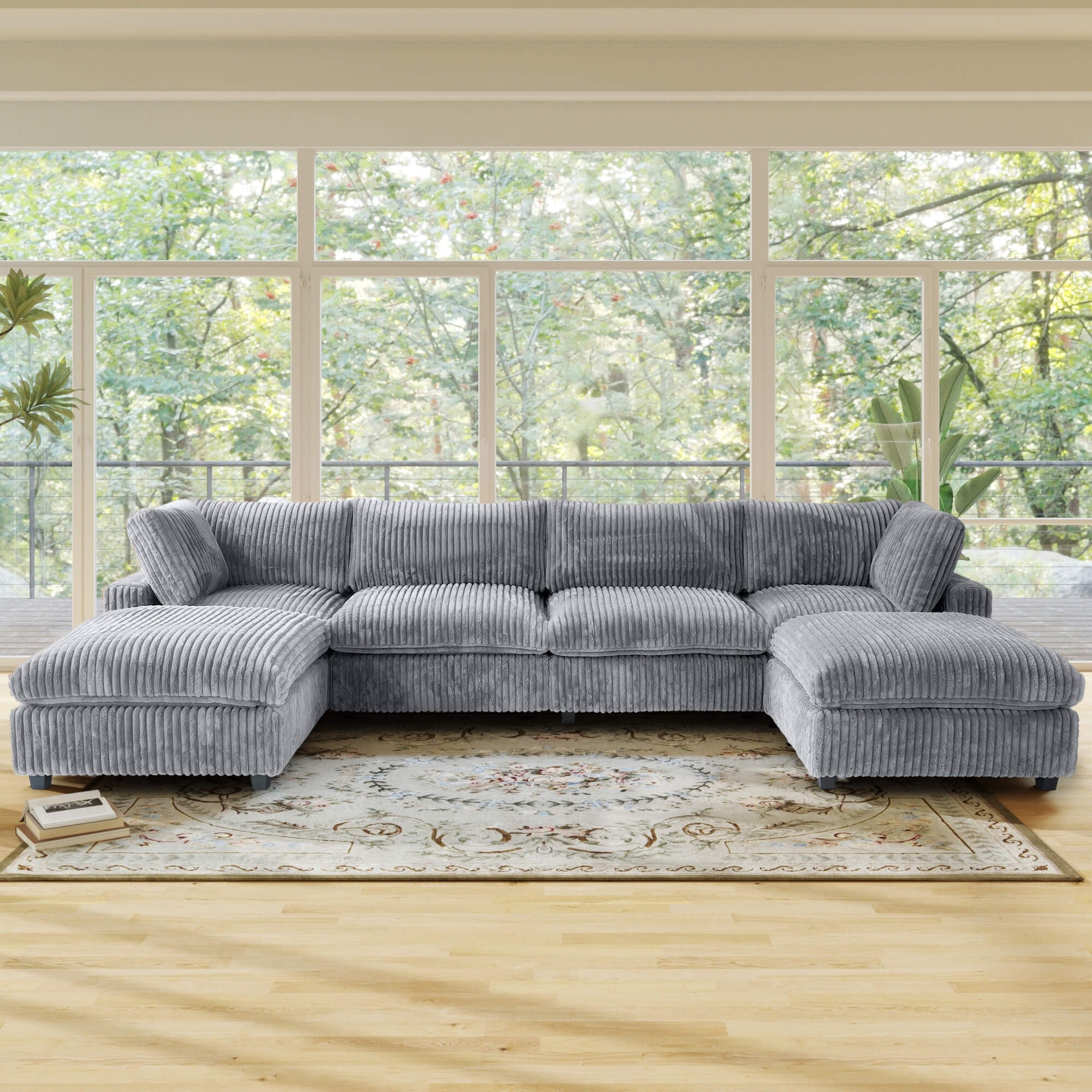 Gray U-shaped sectional sofa in a living room with large windows and a rug.