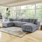 Gray U-shaped sectional sofa in a living room with large windows and a rug.
