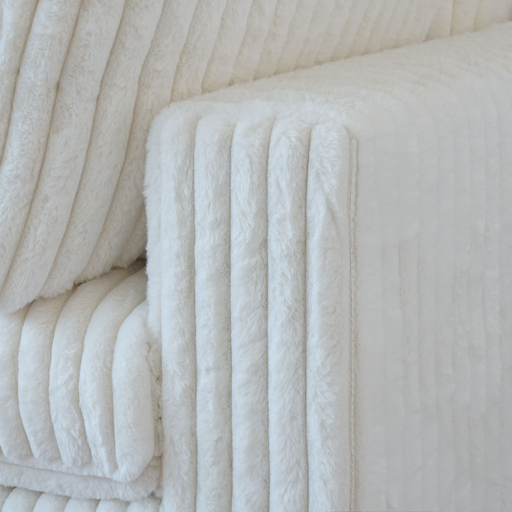 Close-up of a wide armrest of a white faux rabbit fur sofa
