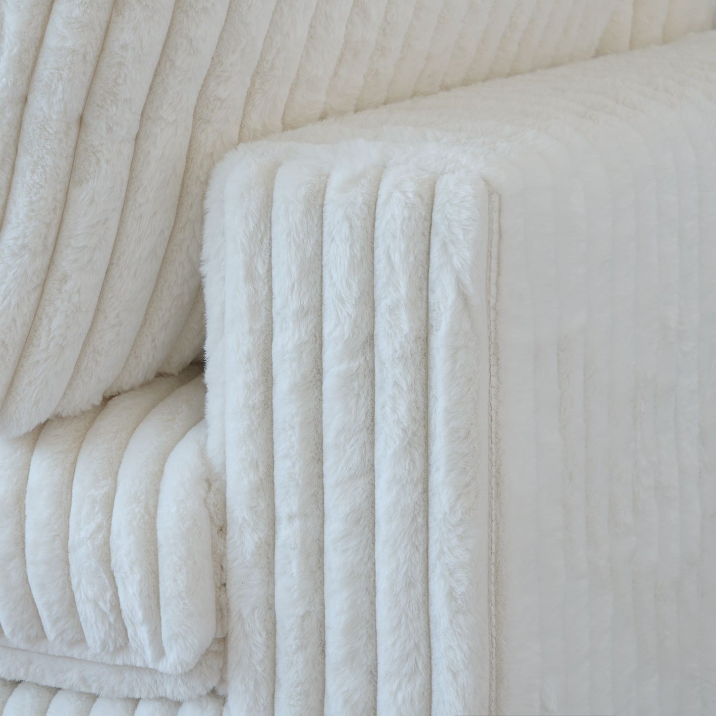 Close-up of a wide armrest of a white faux rabbit fur sofa
