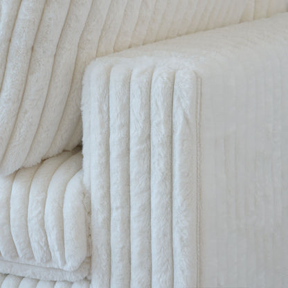 Close-up of a wide armrest of a white faux rabbit fur sofa