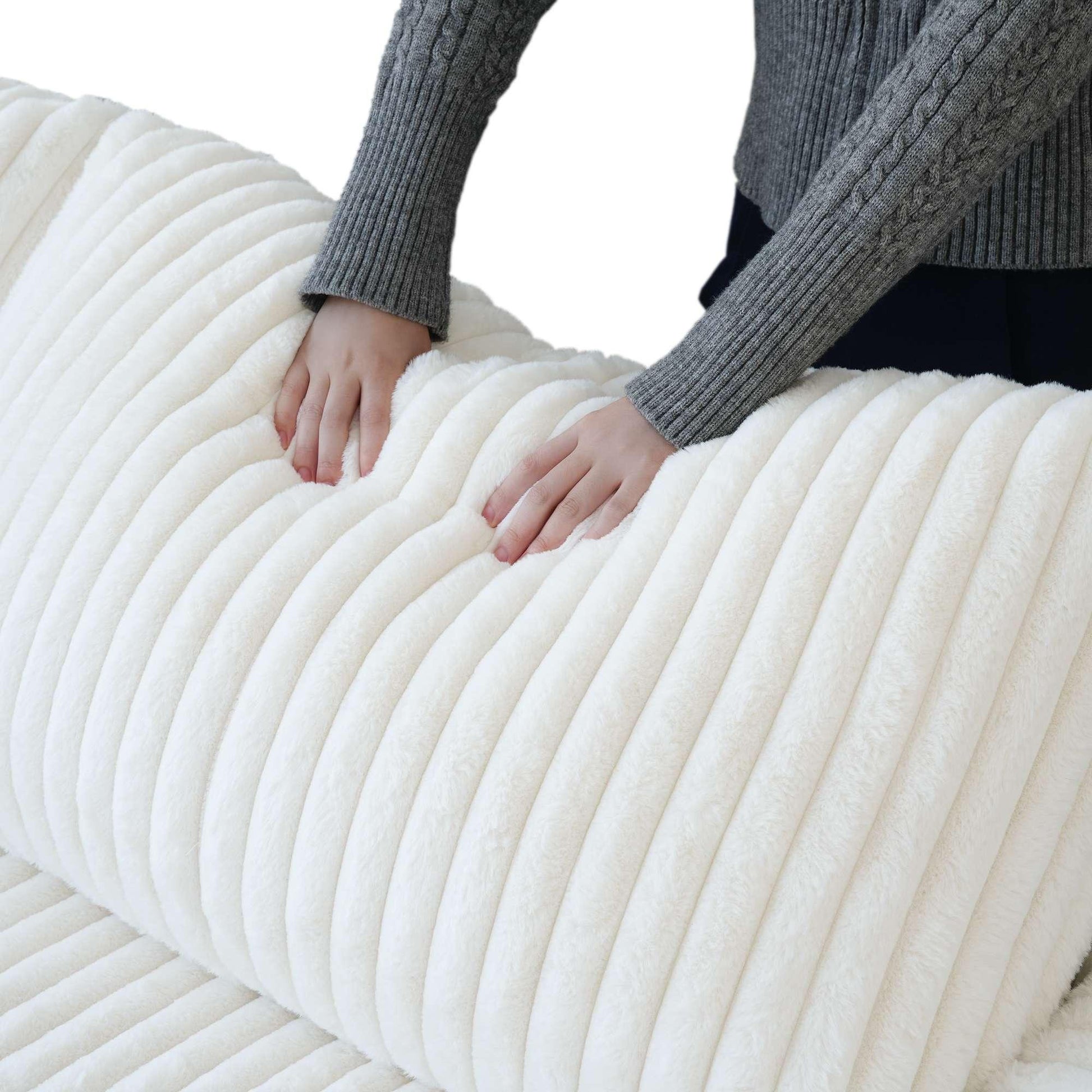 Person pressing on a backrest cushion of a white faux rabbit fur sofa