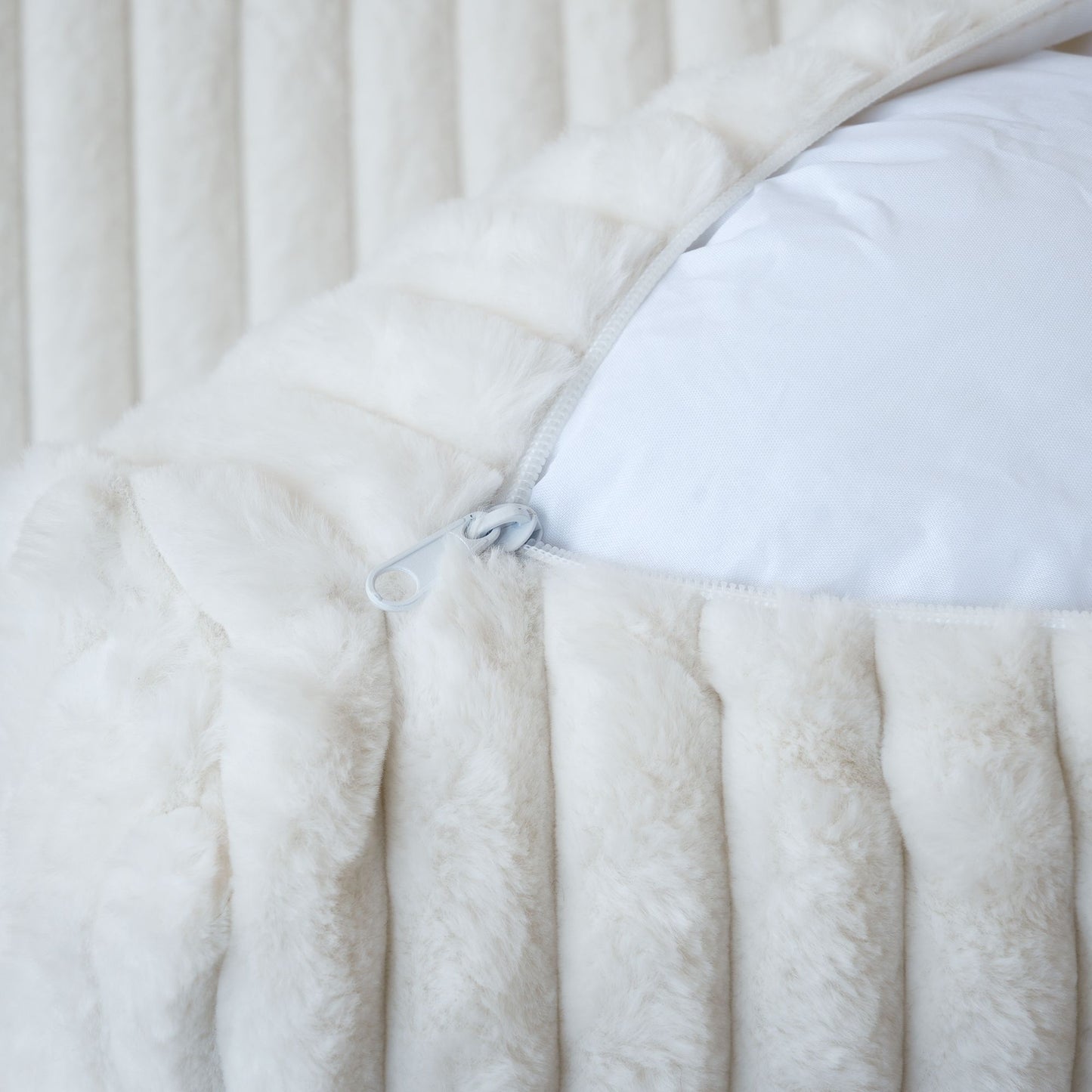Close-up of an unzipped cover of a white faux rabbit fur sofa
