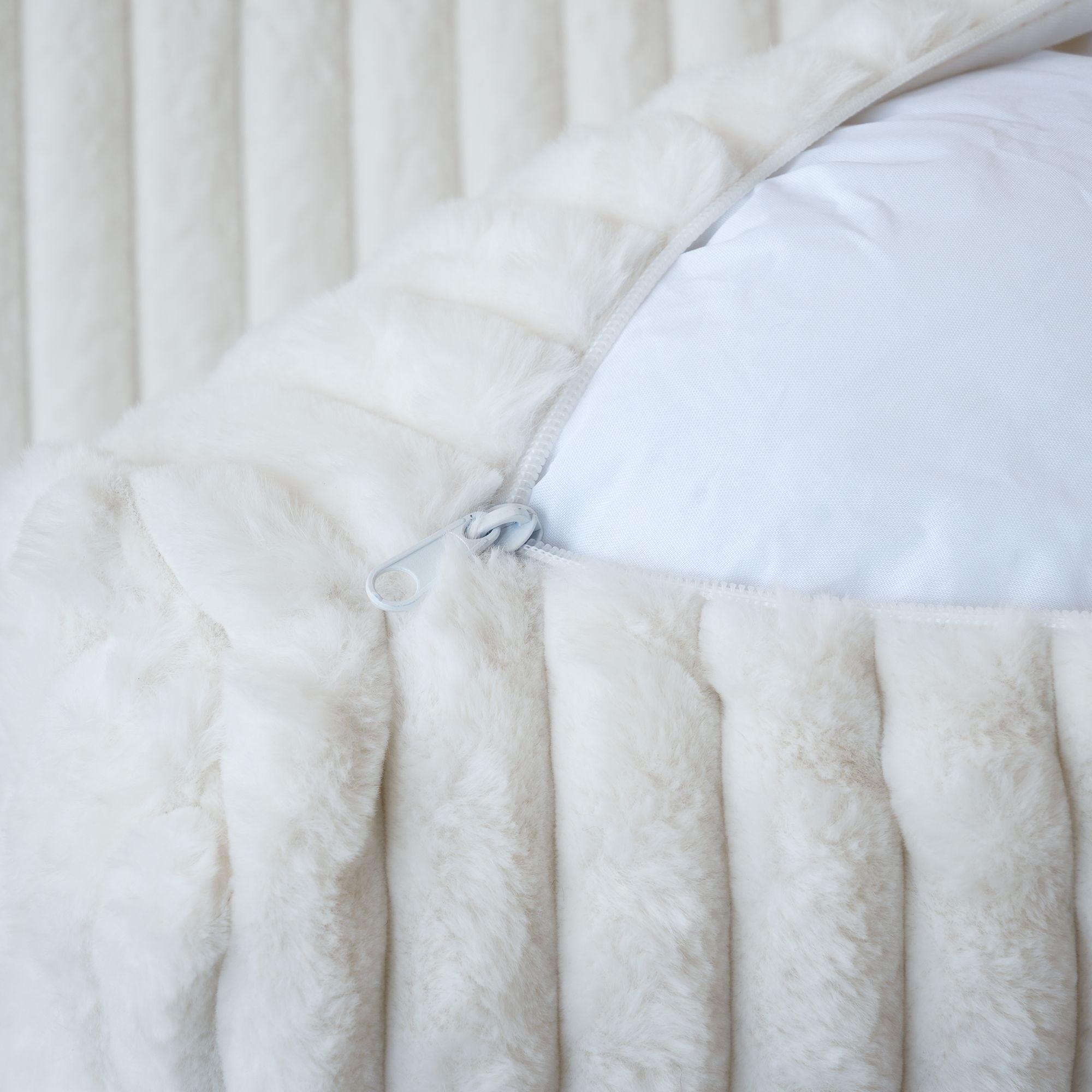 Close-up of an unzipped cover of a white faux rabbit fur sofa