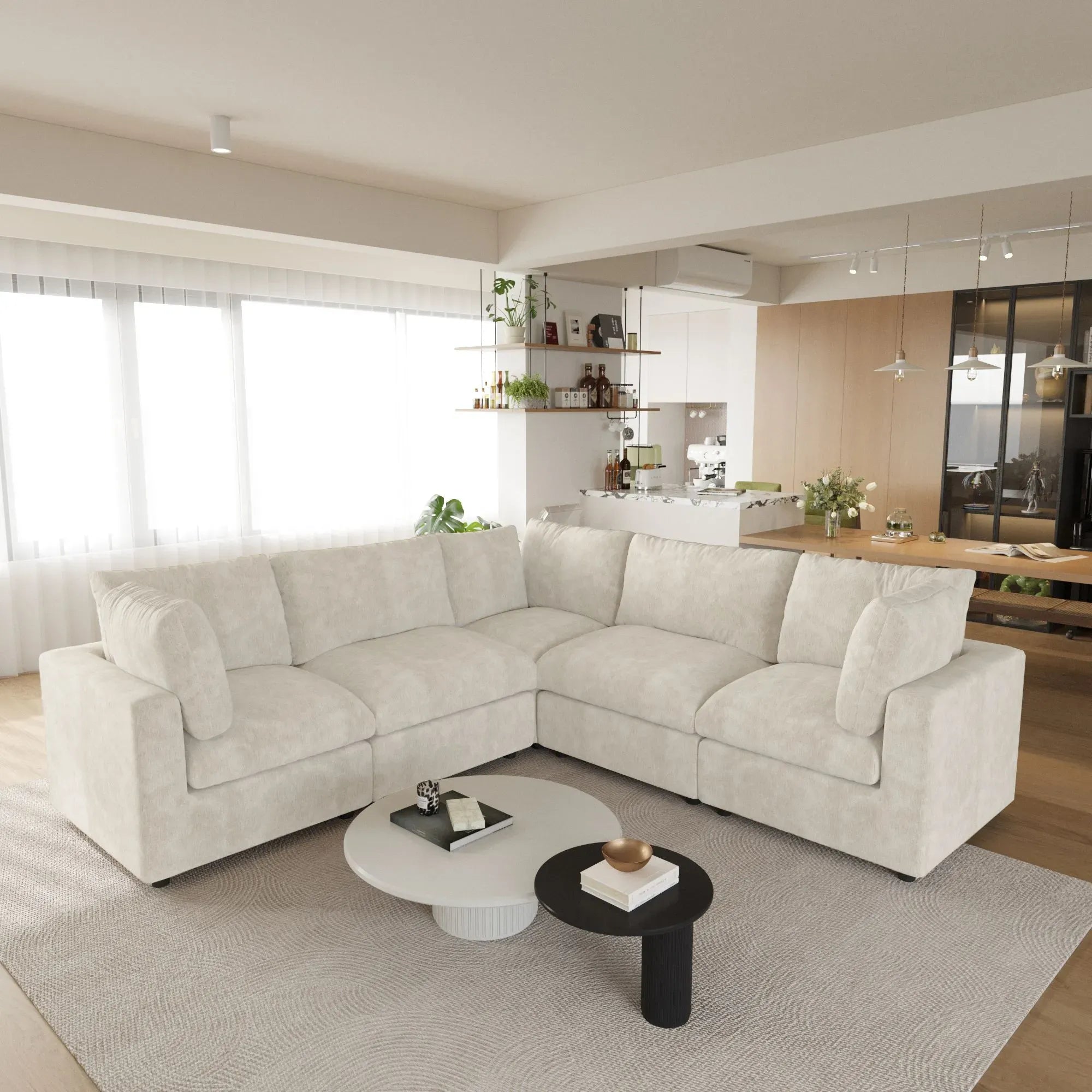 Modern living room with a beige 5-seater corner sectional sofa, coffee table, and kitchen in the background.