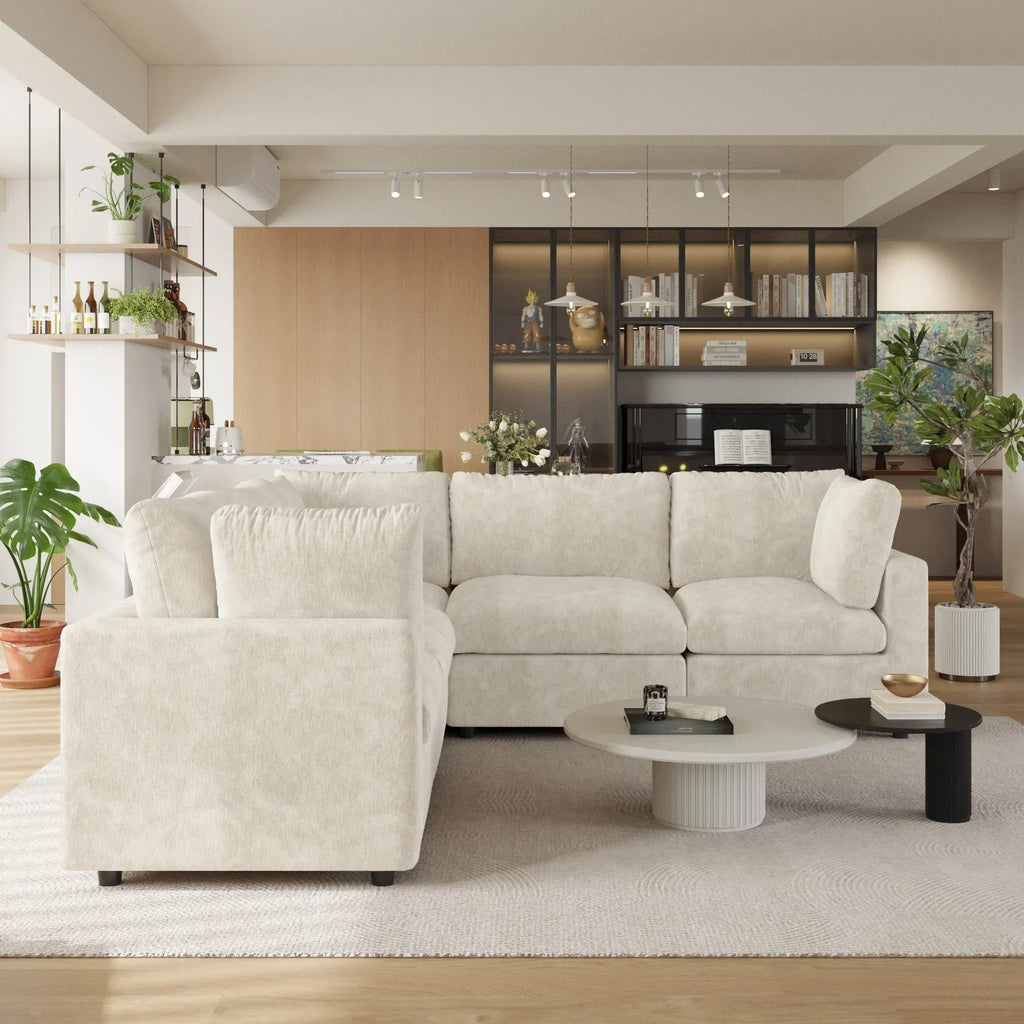 Modern living room with a beige 5-seater corner sectional sofa, coffee table, and decorative items.