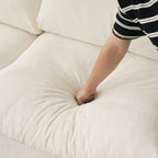 Person pressing on a seat cushion of a beige sofa