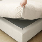 Person holding up a seat cushion of a beige sofa