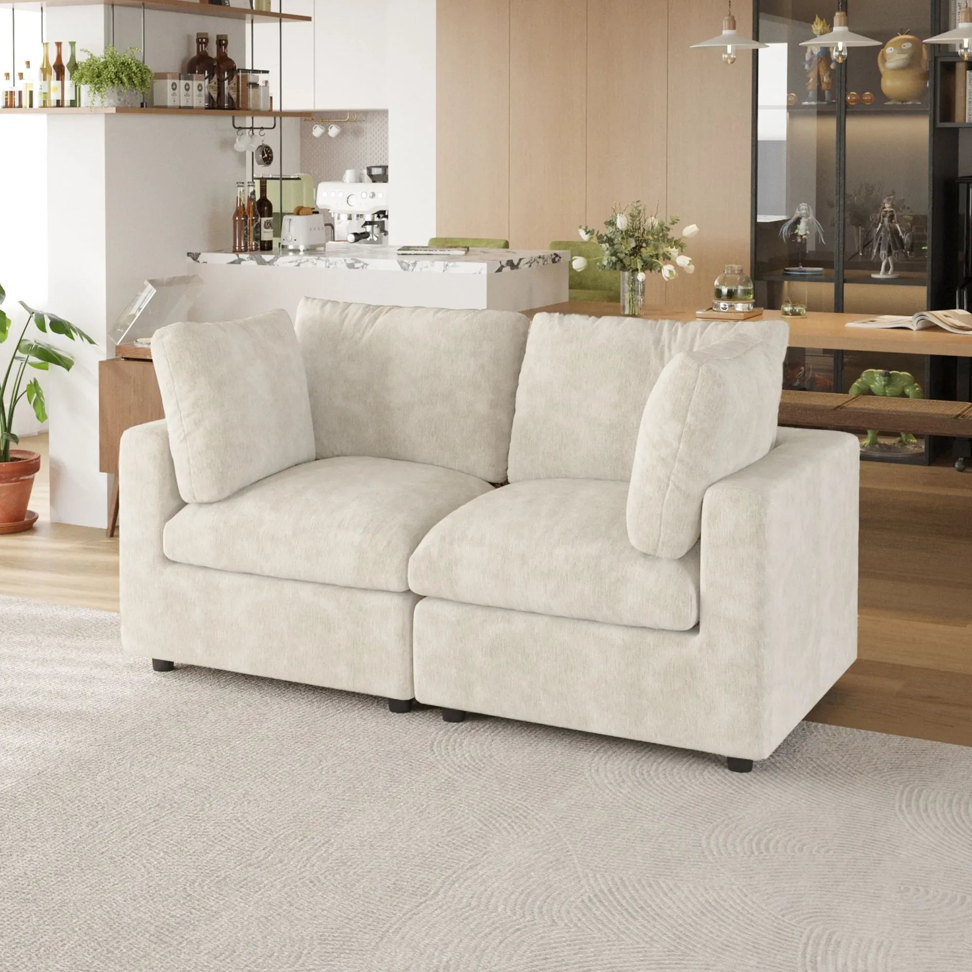 Beige sofa in a living room with a kitchen in the background