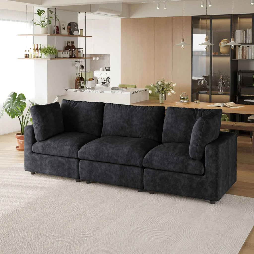 Black 3-seater sofa in a modern living room with a kitchen in the background