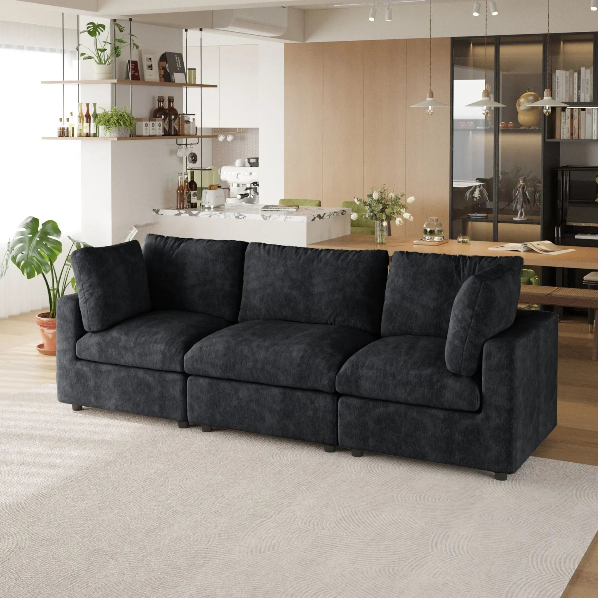 Black 3-seater sofa in a modern living room with a kitchen in the background
