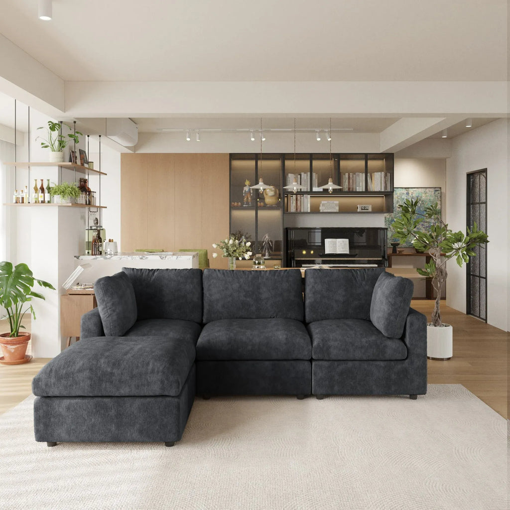 Black L-shaped 4-seater sectional sofa in a modern living room with kitchen in the background