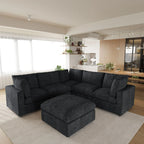 Black V-shaped corner sectional sofa with ottoman in a modern living room with a kitchen in the background.