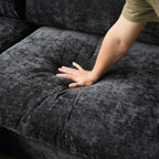 Person's hand touching a black textured sofa