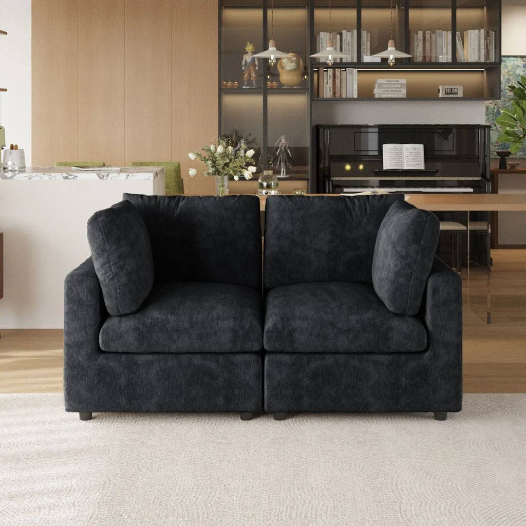 Black sofa in a living room with a bookshelf and piano in the background