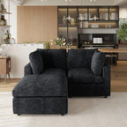 Black sectional sofa in a modern living room with a kitchen in the background.