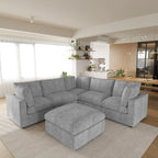 Gray V-shaped corner sectional sofa with ottoman in a modern living room with kitchen in the background