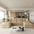 Modern living room with khaki U-shaped 6-seater sectional sofa, coffee table, and kitchen in the background.