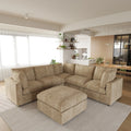 Khaki V-shaped corner sectional sofa with ottoman in a modern living room with kitchen in the background