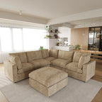 Khaki V-shaped corner sectional sofa with ottoman in a modern living room with kitchen in the background