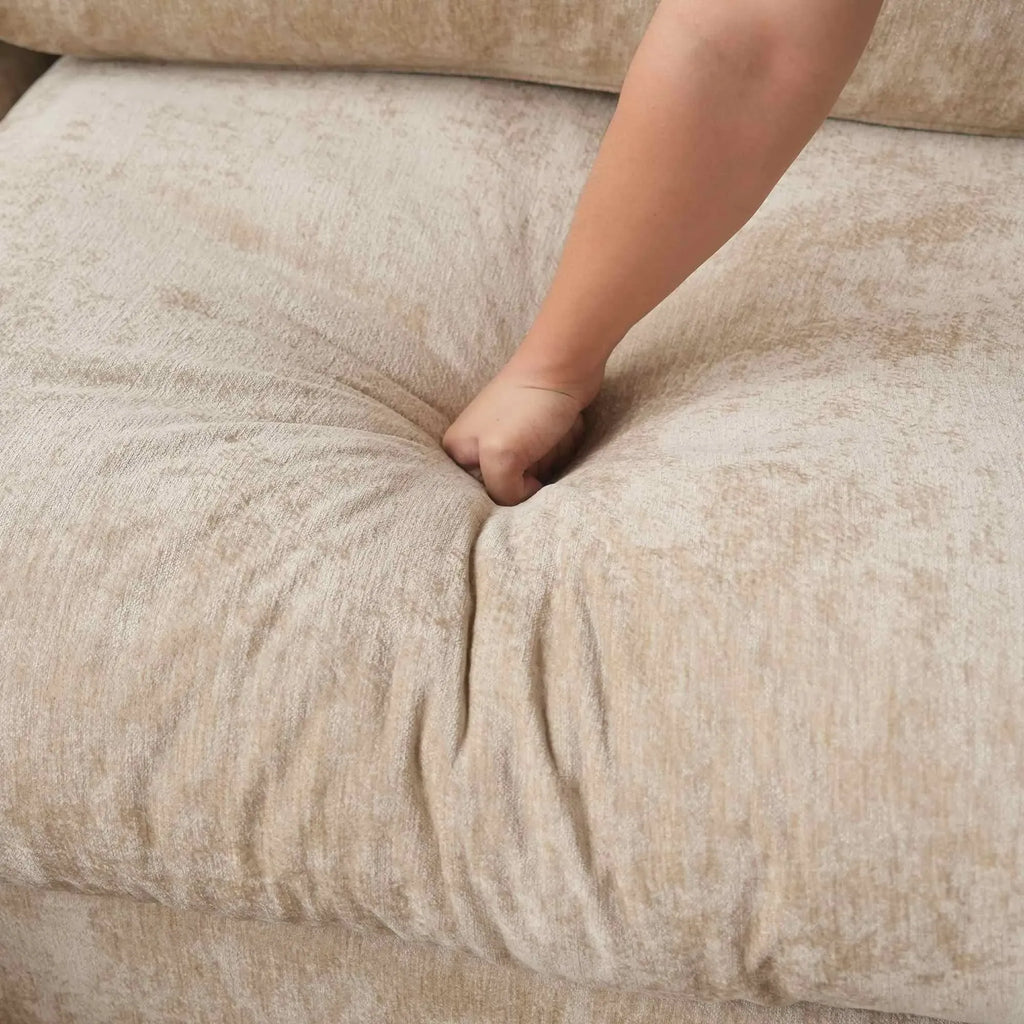 Close-up of a hand pressing onto seat cushion of a khaki colored sofa
